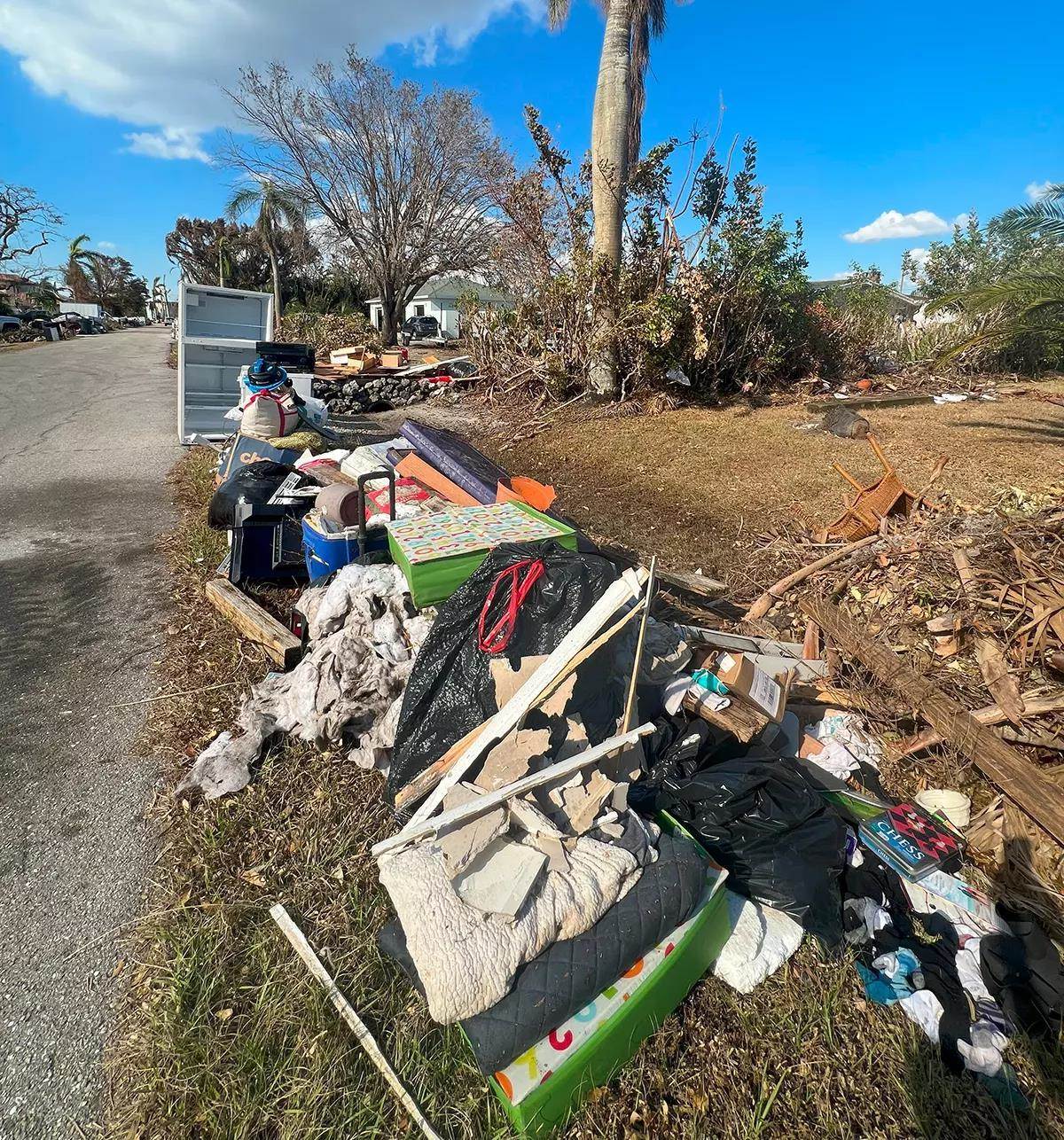 The side of a road littered with destroyed appliances, toys, and furniture. 