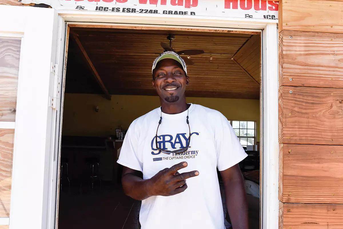 A Bahamian guide gives a peace sign, standing in a doorway. 