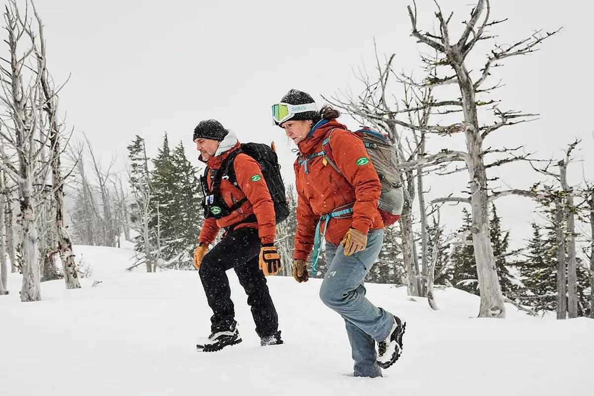 Two people hiking in snow in a mountain environment. 