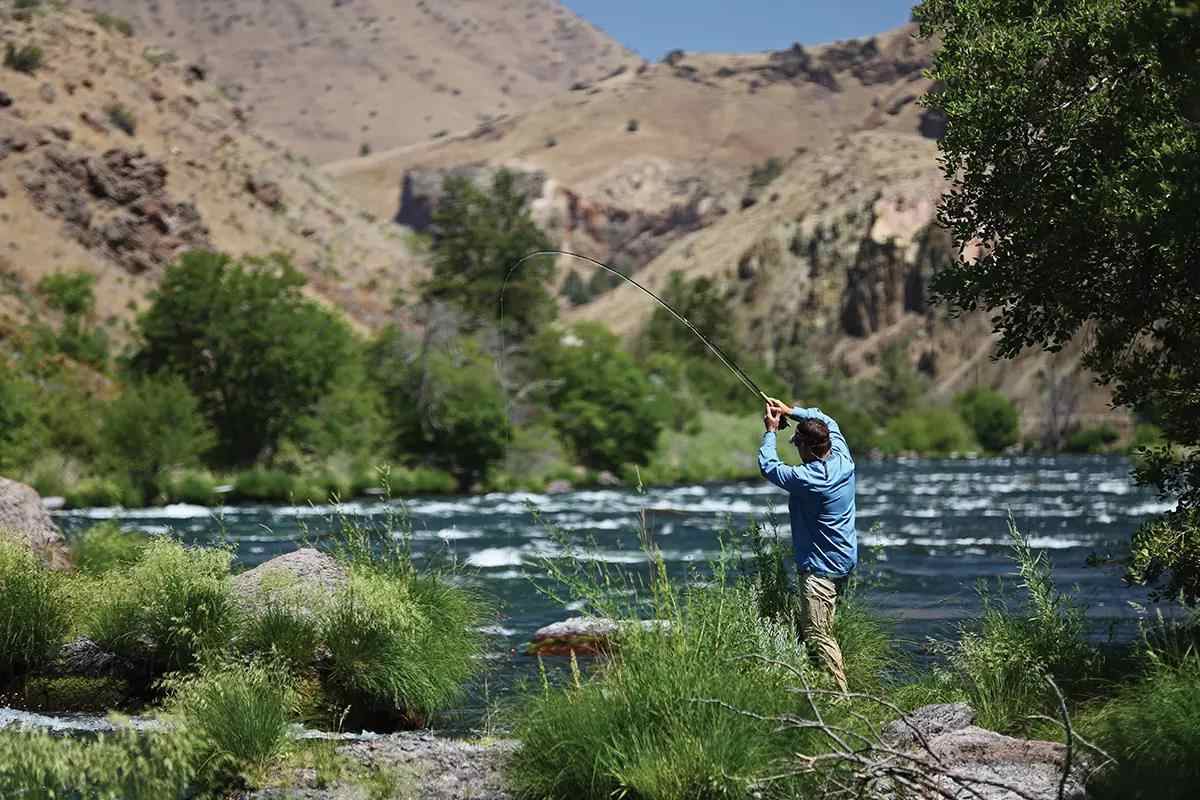 A fly angler hooked up to a trout on a rapid desert river. 