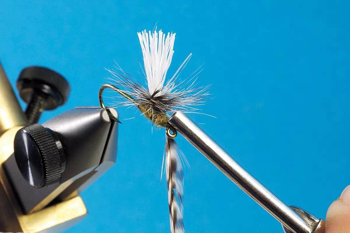 A small dry fly in a vise, in the tying process.