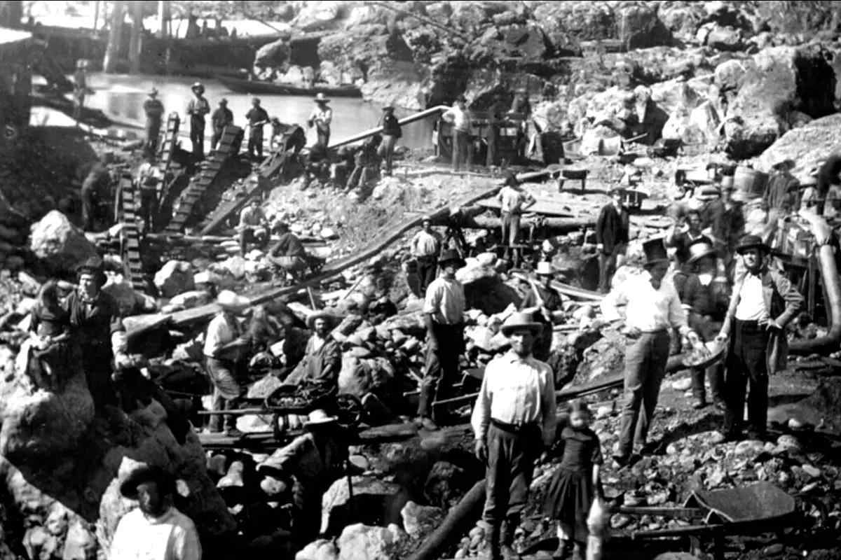 An old timey black and white photo of hydraulic mining on the American River during the gold rush.