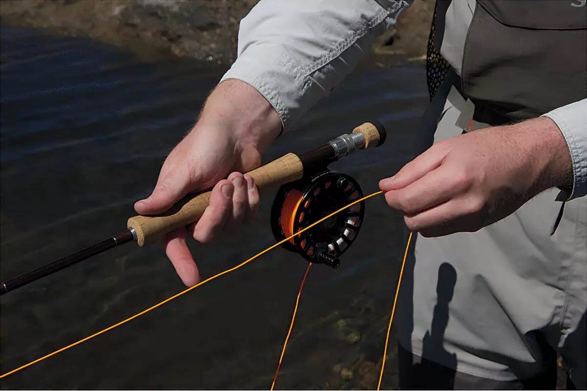 A man's hands holding a fly rod, demonstrating a fly retrieve.