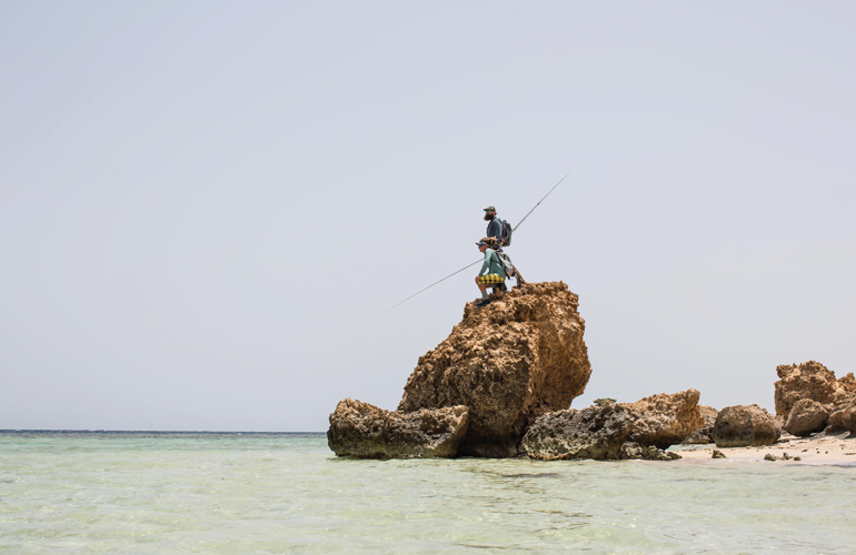 Two fly anglers standing on a large rock on some saltwater flats