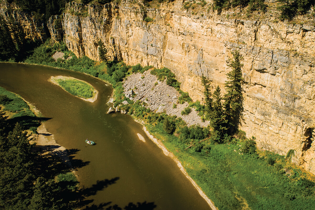 aerial view of Montana's Smith River; raft floating downstream beneath tall limestone cliffs